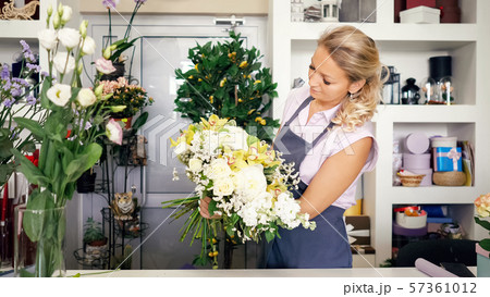 Florist woman creates lovely flower bouquet with roses, leaves and gypsophila. Florist woman creates lovely flower bouquet with roses, leaves and gypsophila. 57361012