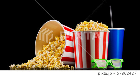 Paper striped bucket with popcorn, cup of drink and glasses isolated on black 57362427