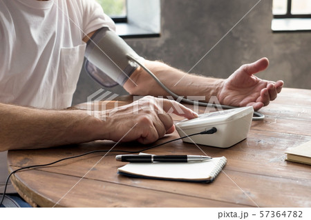 Man using a home blood pressure machine to check his health sitting at living room Man using a home blood pressure machine to check his health sitting at living room 57364782
