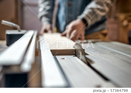 Man making wooden parts for furniture on thickness planer machine. 57364799