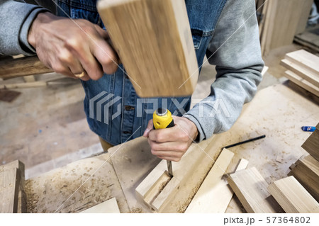 carpenter makes a hole in the wooden furniture detail with a hammer and chisel. carpenter makes a hole in the wooden furniture detail with a hammer and chisel. 57364802
