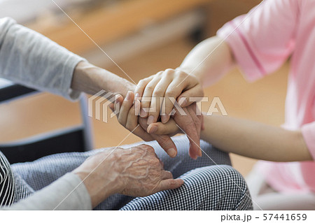 シニア女性の手を握る女性の手の写真素材