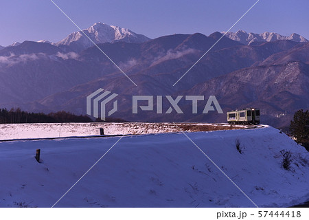 北杜市小淵沢町、朝日の中、雪の大カーブを行く小海線列車 57444418