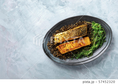 Roasted salmon with sesame seeds, wakame and wild black rice, top shot with a place for text 57452320