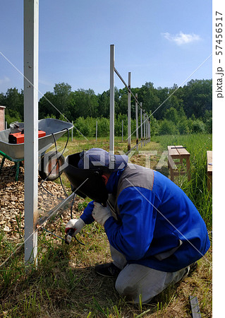 The welder welds a new metal frame for the fence 57456517