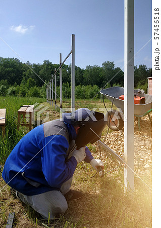 The welder welds a new metal frame for the fence 57456518