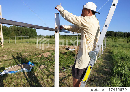 The worker is standing on the ladder and the 57456679