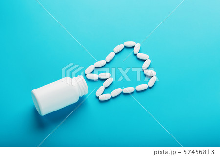 Vitamins with calcium Ca in the form of a tooth are scattered from a white jar on a blue background 57456813