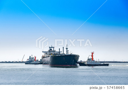 出港する貨物船と綱取り放し作業するタグボート 57458665