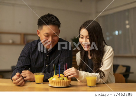 フルーツケーキで誕生日を祝う若いカップルの写真素材