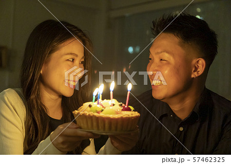 フルーツケーキで誕生日を祝う若いカップルの写真素材