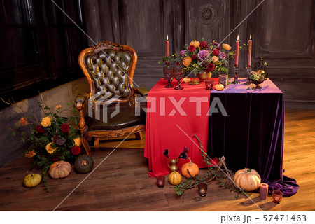 Halloween pumpkin decor with candles and a bouquet of flowers in a bronze vase on a red tablecloth. Halloween pumpkin decor with candles and a bouquet of flowers in a bronze vase on a red tablecloth. 57471463