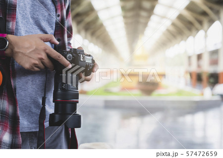 Asian man traveler with backpack holding camera in train station. Asian man traveler with backpack holding camera in train station. 57472659