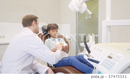 Male dentist educating little boy about dental hygiene Male dentist educating little boy about dental hygiene 57475331