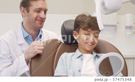 Mature male dentist working with charming young boy 57475348