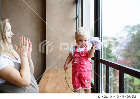 annual girl in a pink jumpsuit hold a hydrangea stand on sill, mom applauds her annual girl in a pink jumpsuit hold a hydrangea stand on sill, mom applauds her 57476682