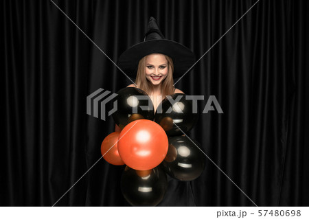 Young woman in hat as a witch on black background Young woman in hat as a witch on black background 57480698