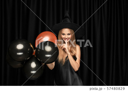 Young woman in hat as a witch on black background Young woman in hat as a witch on black background 57480829