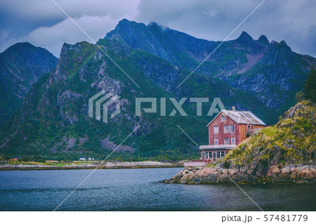 Image of red house at foot of hills, sea, cloudy sky, trees in Norway 57481779