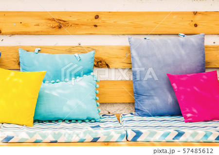 Close up pillows on an outdoor patio chair, with a blue striped cushioned bench Close up pillows on an outdoor patio chair, with a blue striped cushioned bench 57485612