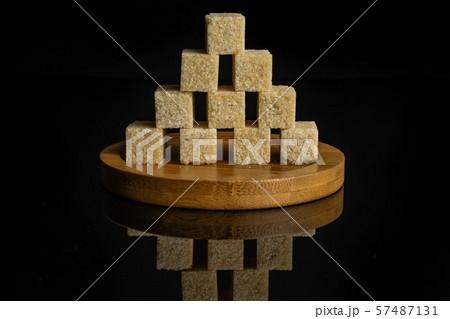 Brown sugar cube isolated on black glass Brown sugar cube isolated on black glass 57487131
