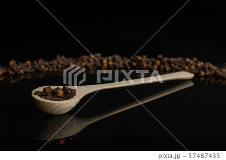 Dry brown clove isolated on black glass Dry brown clove isolated on black glass 57487435