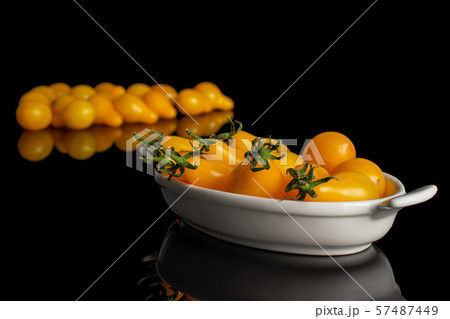 Yellow pear tomato isolated on black glass 57487449