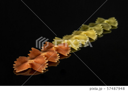 Raw farfalle tricolore isolated on black glass Raw farfalle tricolore isolated on black glass 57487948
