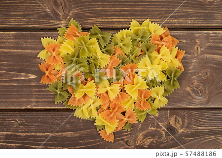 Raw farfalle tricolore on brown wood 57488186