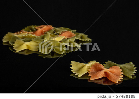 Raw farfalle tricolore isolated on black glass Raw farfalle tricolore isolated on black glass 57488189