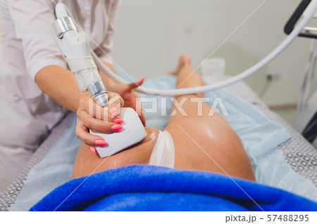 Cropped view of cosmetologist with roller doing buttocks starvac massage. 57488295