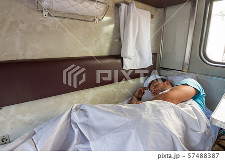 A man sleeps on the bottom shelf in a train car A man sleeps on the bottom shelf in a train car 57488387
