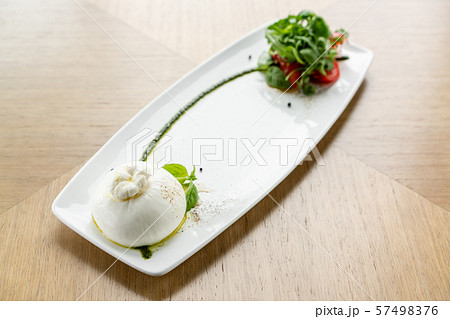 Fresh Salad with tomatoes, basil, burrata, and olive oil on wooden background. Italian traditional Fresh Salad with tomatoes, basil, burrata, and olive oil on wooden background. Italian traditional 57498376