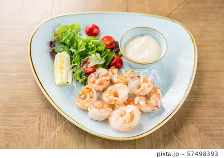 Delicious fresh seafood shrimp with fresh vegetables and lime. Plate on wooden table. Cream sauce Delicious fresh seafood shrimp with fresh vegetables and lime. Plate on wooden table. Cream sauce 57498393
