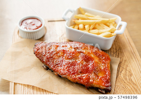 Delicious Pork ribs. Full rack of ribs BBQ on wooden plate with french fries and salad 57498396