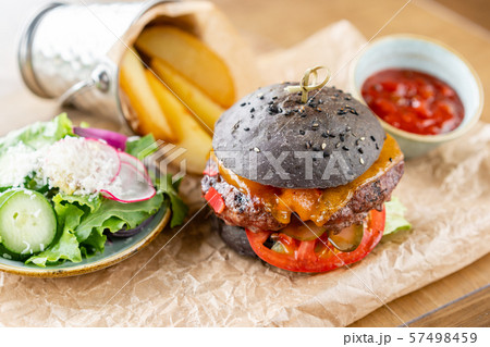 Cheeseburger with lettuce, tomato, fries, and melted cheese. The table in the restaurant. Unhealthy 57498459