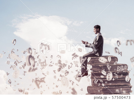 Businessman or student on book and symbols flying around Businessman or student on book and symbols flying around 57500473