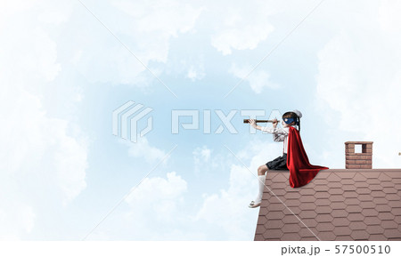 Girl power concept with cute kid guardian against cloudscape background. Mixed media 57500510