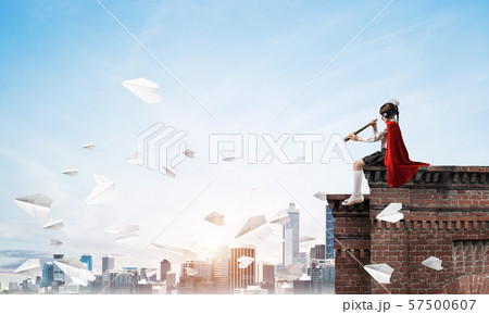 Girl power concept with cute kid guardian against cityscape background. Mixed media 57500607