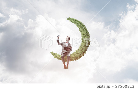 Young businessman or student on moon in sky studying the science 57500812