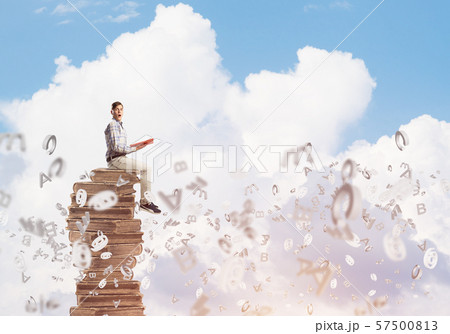 Man student on stack reading book and symbols flying around 57500813