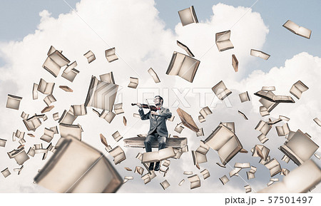 Handsome violinist sitting on book and play his melody Handsome violinist sitting on book and play his melody 57501497