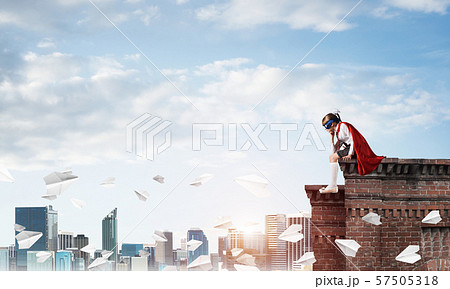Girl power concept with cute kid guardian against cityscape background. Mixed media 57505318