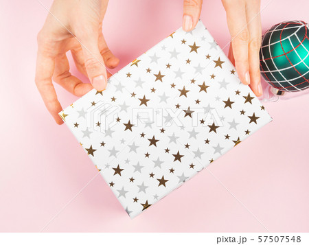 Gift box and christmas ornament on pink, hands 57507548