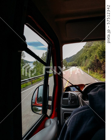 Image from passenger compartment of car driving along road among green trees in Norway on summer. 57512342