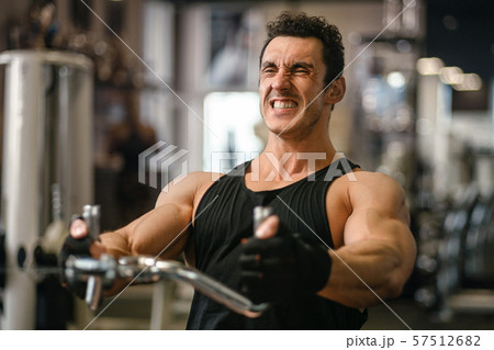 Man lifting weights at the cable machine in a gym. 57512682
