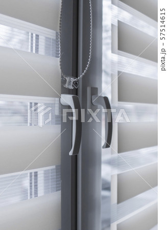 Window handle and white fabric roller blinds on the white plastic window in the living room. Close 57514615