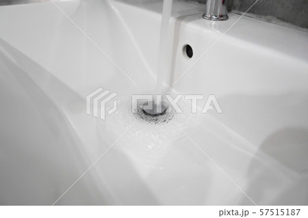 Running water from modern stainless steel faucet in white sink. Counter bathroom interior 57515187