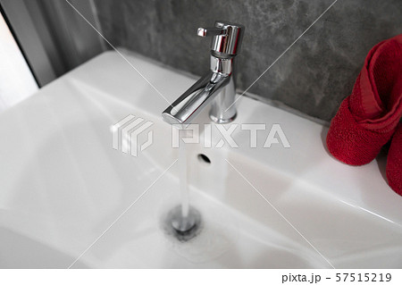 Running water from modern stainless steel faucet in white sink. Counter bathroom interior Running water from modern stainless steel faucet in white sink. Counter bathroom interior 57515219