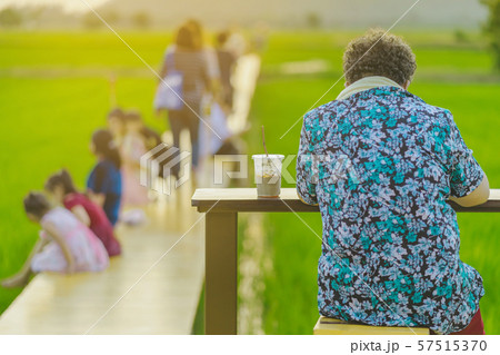 Back view of senior woman sit for resting and waiting for time to take photos of the sunset on the farmer's balcony in the rice fields. 57515370